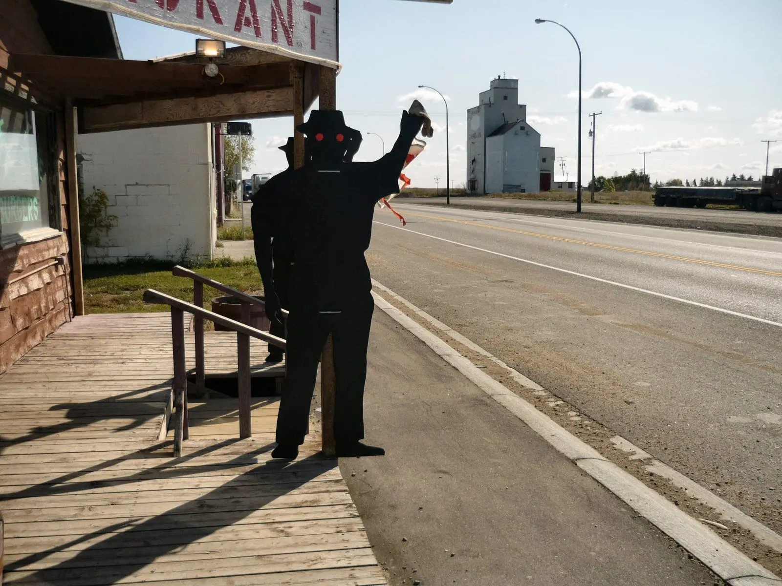Plywood figure outside restaurant on Highway 11 with grain elevator